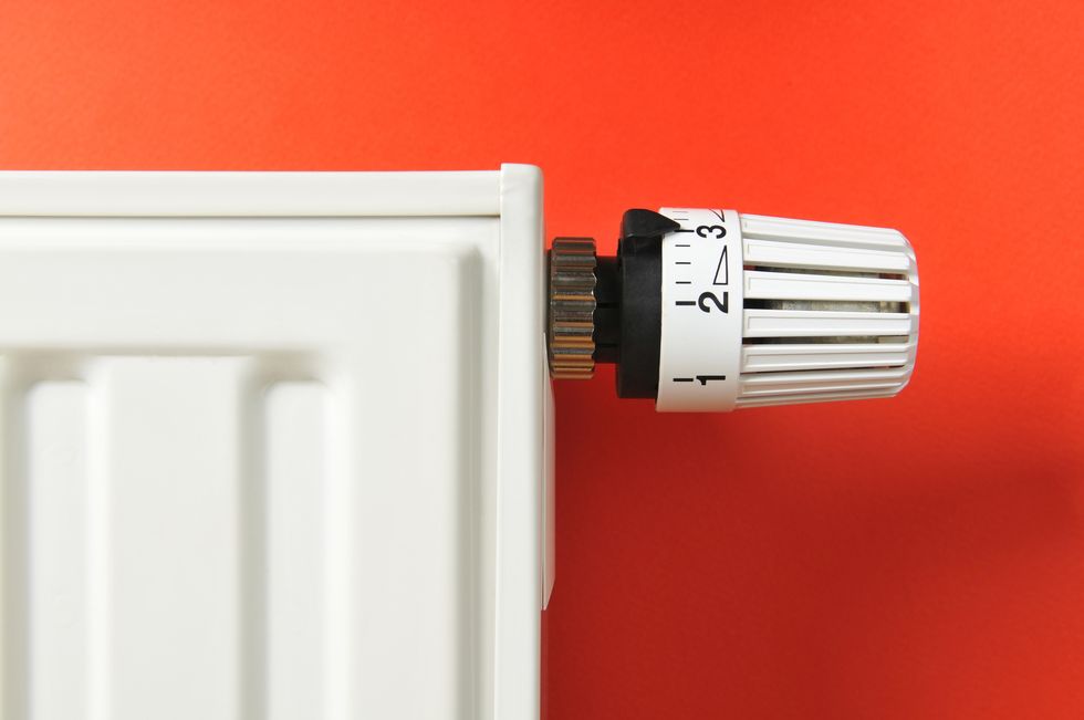 Close-up of white thermostat and radiator on red background