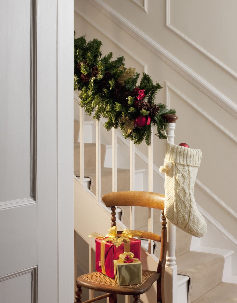 Christmas gifts and stocking near staircase in hallway