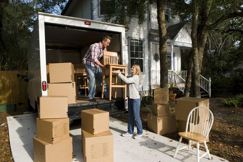 Mid adult couple unloading chairs and cardboard boxes from the moving van