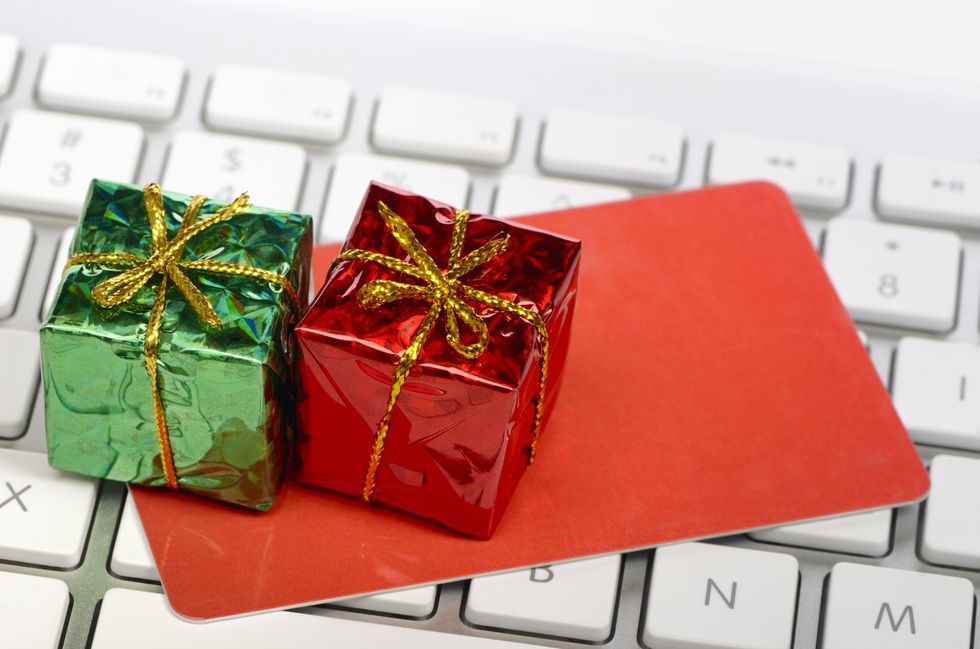 Holiday concept online shopping - miniature gift boxes and credit or gift card on top of computer keyboard.