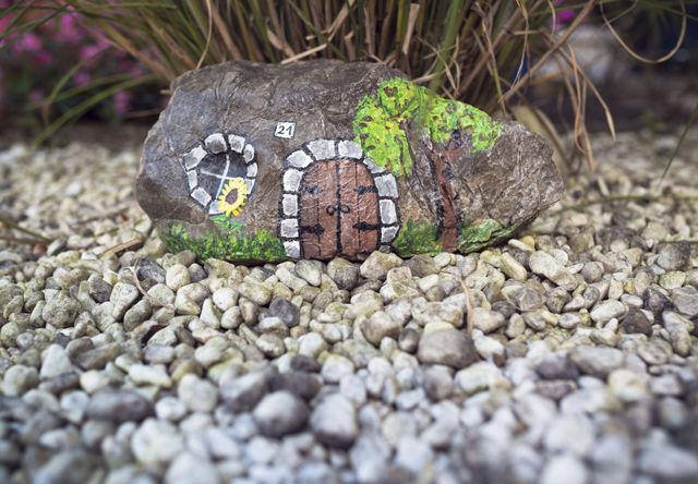 Stone painted as little house in garden