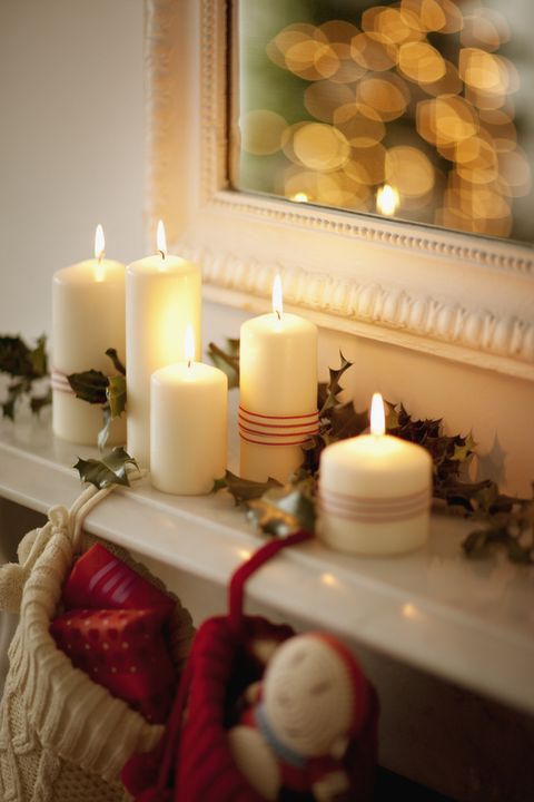 Candles lit on mantelpiece with Christmas stockings