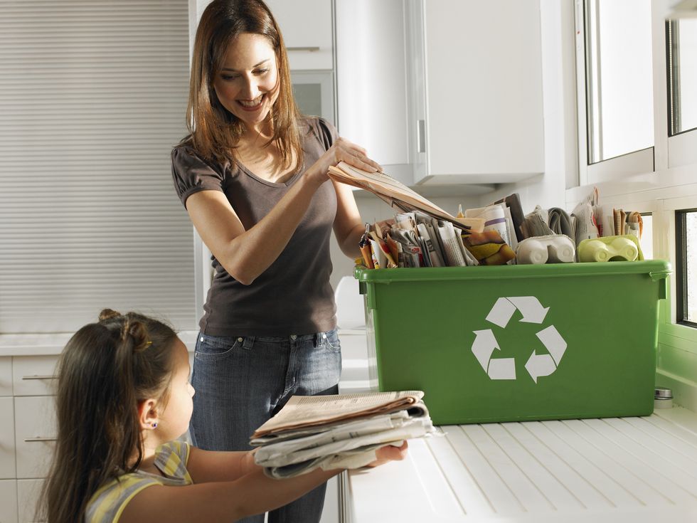 Mother and daughter sharing recycling duties in domestic kitchen