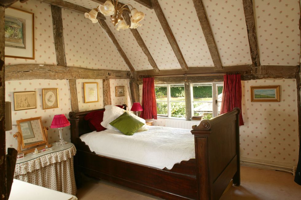 Bed in country house bedroom with sloping ceiling and wooden beams