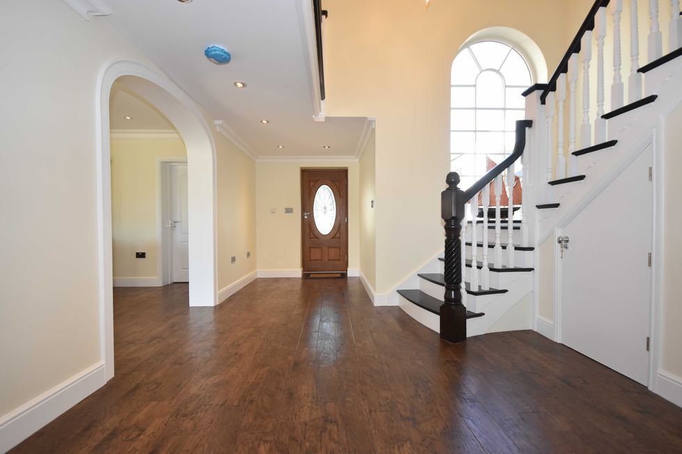 Staircase and arched door ways in entrance hall of house with wooden floors