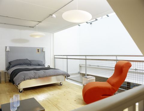 Modern bedroom with grey duvet cover and bright orange chair