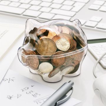 A see through Piggy bank with money on a desk