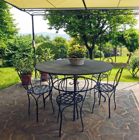 Covered patio with view on garden: Cosy garden corner with round wrought iron table and chairs, shaded by awning