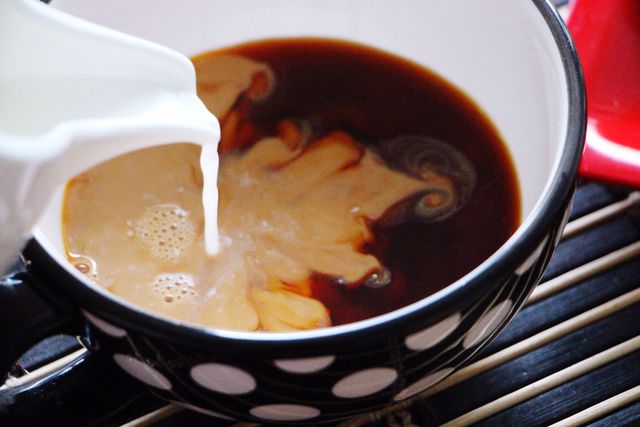 Close-Up Of Milk Pouring Into Tea Cup