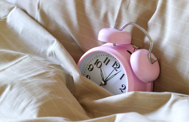 Pink alarm clock in bed