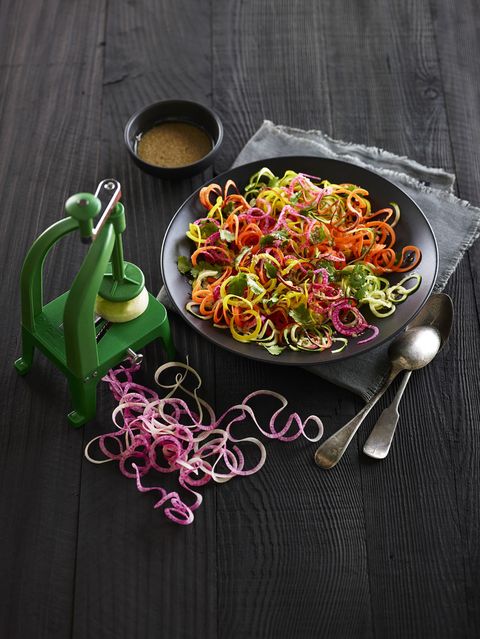 Green Spiralizer tool on black table with colourful food