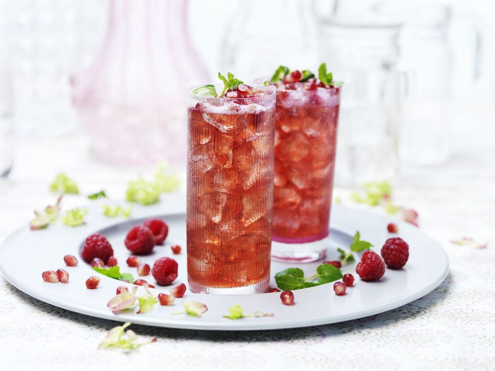 Two glasses of port punch with ice, fresh raspberries and pomegranate