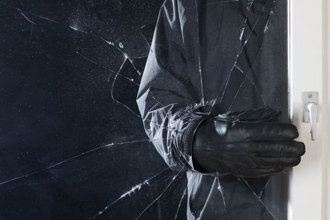 A criminal breaking into a window, focus on hand