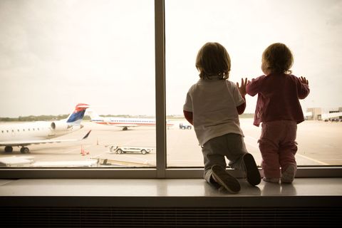 Two children look out the window at an airport