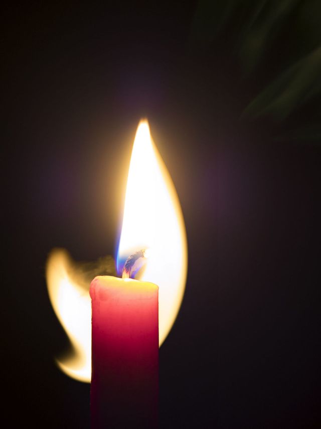 Candle of red color with his flame ignited in movement