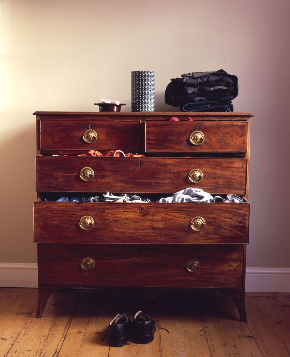 Shoes on floor by chest of drawers with drawers pulled open
