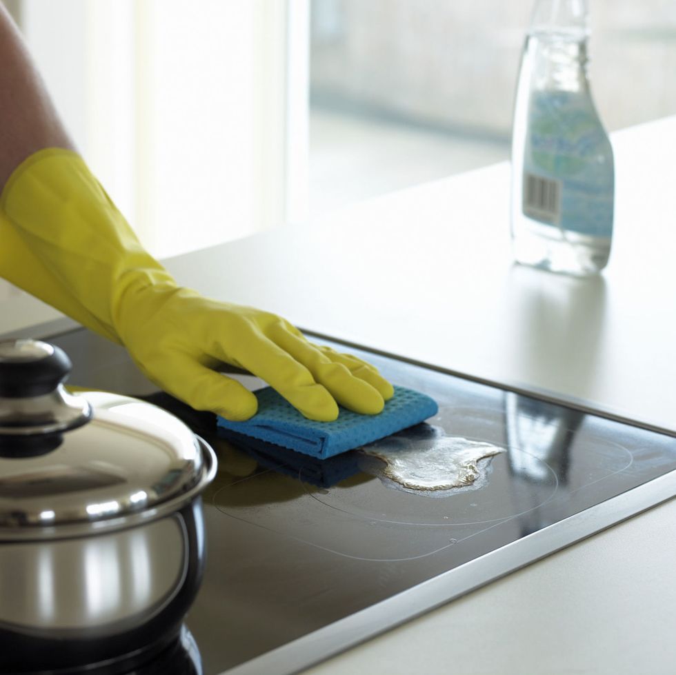 Gloved Hand Cleaning a Hob With Disinfectant
