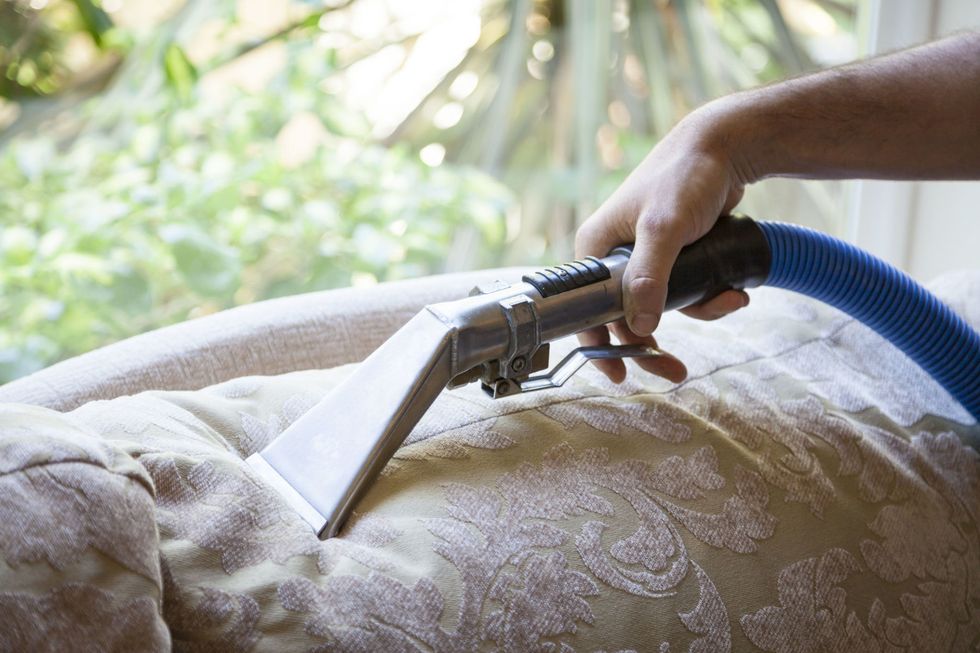 Man cleaning sofa pillow with steam cleaning in home