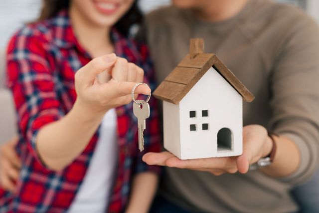 Couple with keys and wooden house modelling