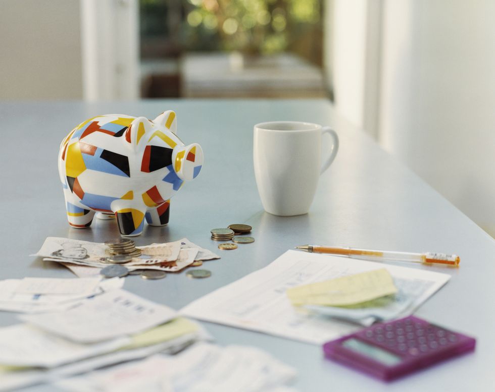 Piggybank, British Currency, Calculator, Receipts and a Mug on a Table