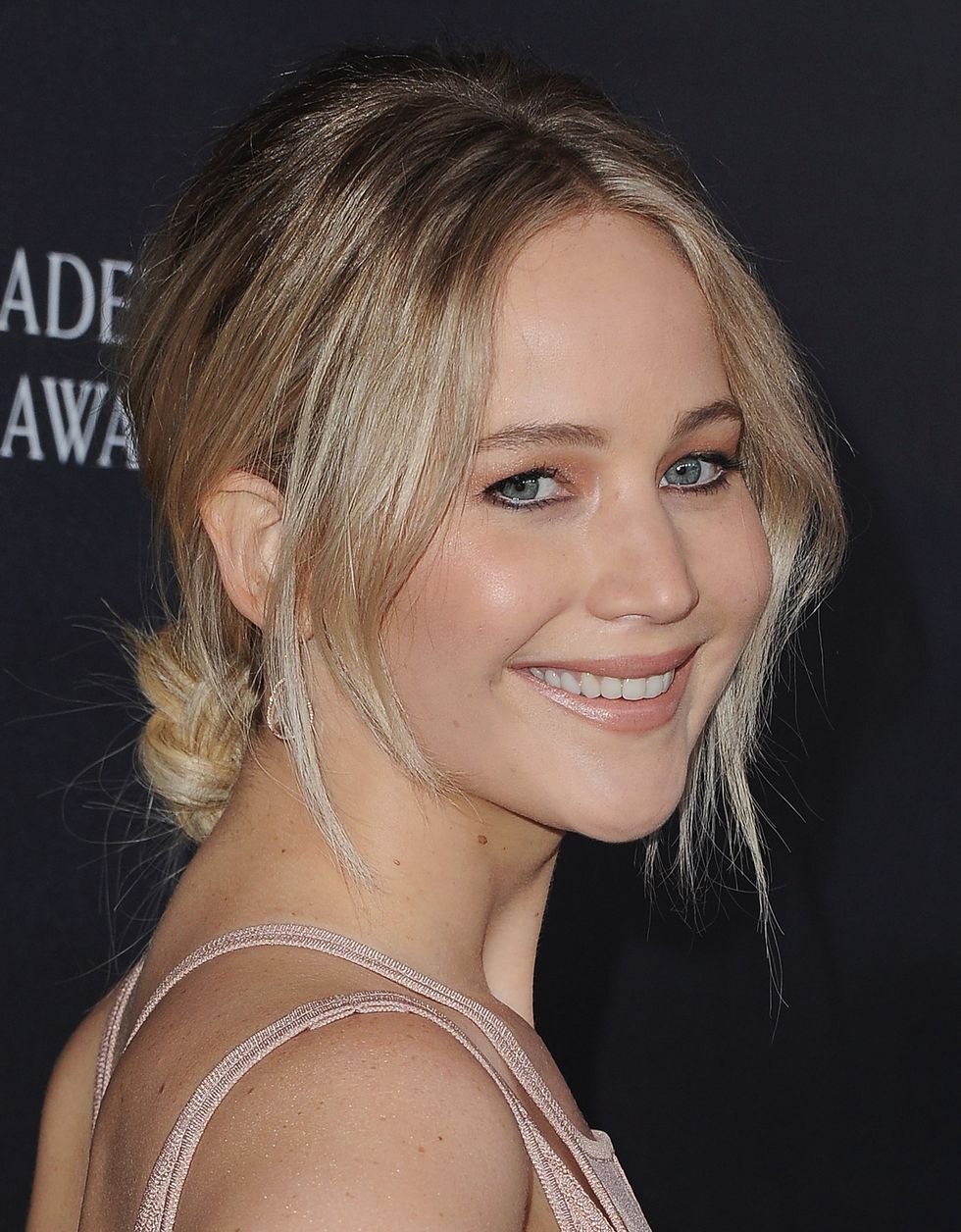 if you have straight or wavy hair, nailing jlaw's look is as easy as center parting the hair, twisting it back into a low knot aka a banana bun, securing it with as many u pins as necessary, then pulling out a wispy section on either side of the face if the face framing strands need finessing, add a subtle bend with a flat iron or try the wave formation technique with a large barrel curling iron