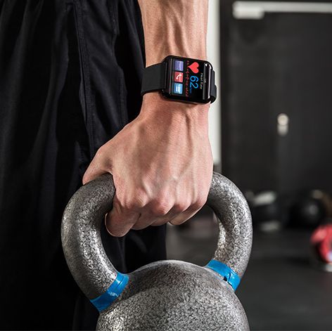 man carrying a kettlebell wearing a fitness tracker on his wrist