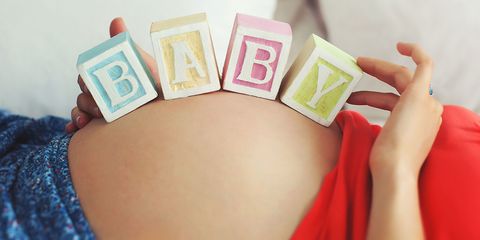 Baby bump with toy blocks spelling BABY