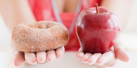 Close up of woman holding doughnut and apple