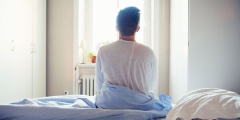 Man sitting in bed in morning waking up