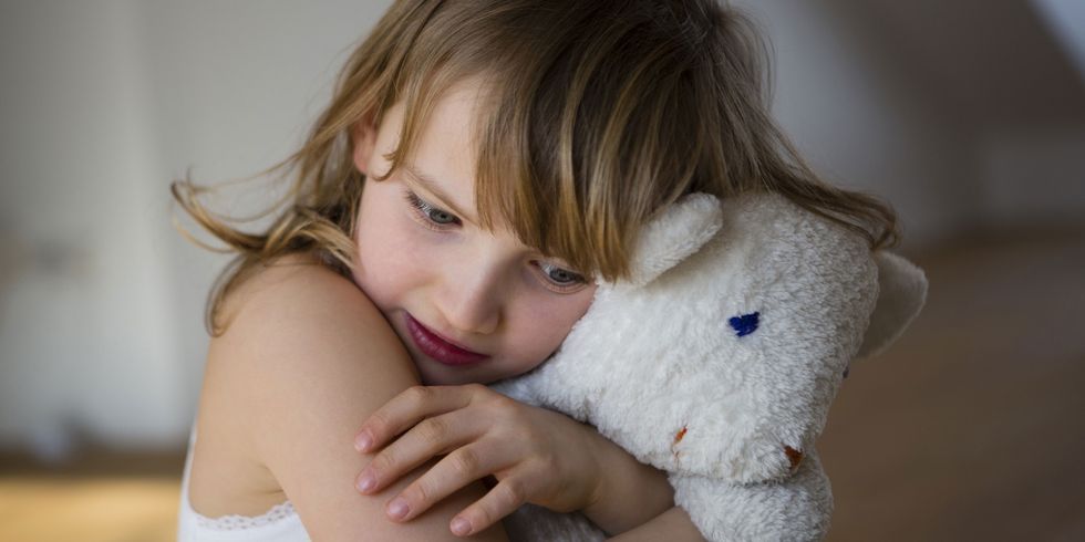 Young girl cuddling toy bear