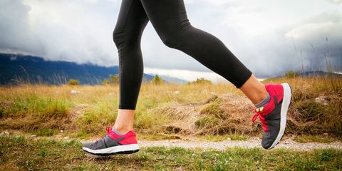 Macro of woman legs in sport shoes, running over the wild terrain, under the cloudy sky