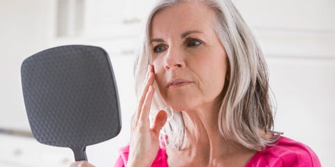 Older woman looking at her face in the mirror