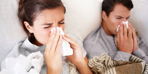 Poorly couple with flu sneezing on sofa