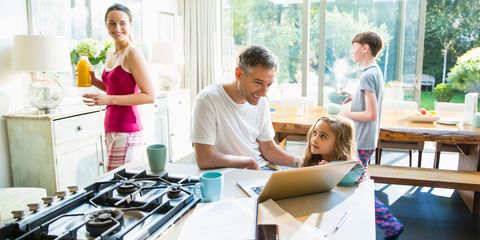 Family with breakfast and laptop in morning kitchen