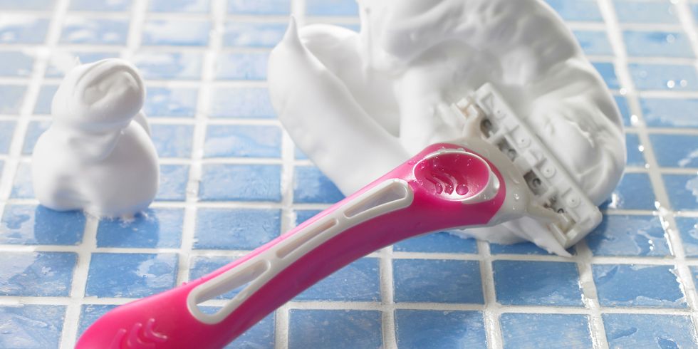 Pink woman's razor on blue bathroom tiles