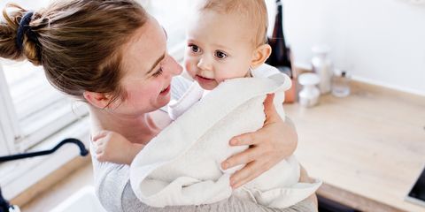 Mother carrying baby son wrapped in towel