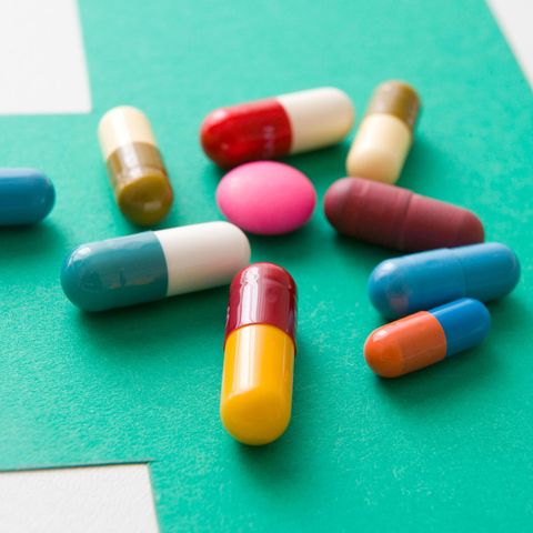 Mixed coloured pills on green background