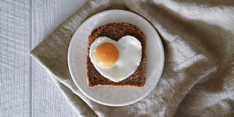 Slice of bread with egg in heart shape on plate