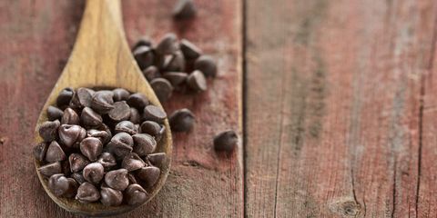 Chocolate chips in wooden spoon on wood table