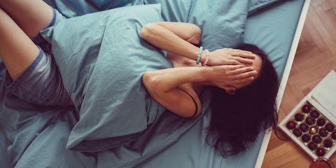 Woman in bed covering face