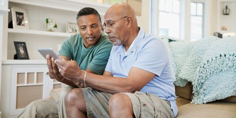 Son Helping Senior Father To Use Digital Tablet