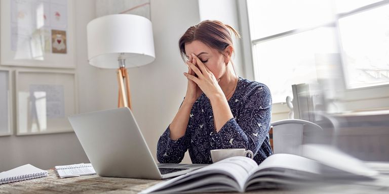 Stressed woman at work on laptop head in hands