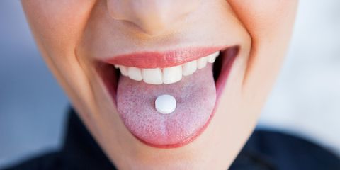 Woman with pill on tongue smiling close up