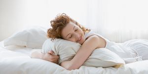 Sleeping smiling woman hugging pillow