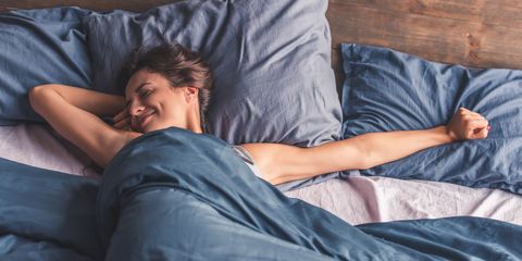 Happy woman in bed smiling and stretching