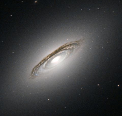 A view of lenticular galaxy NGC-6861 -- flat and disk like, with a bright galactic core. The view is from the bottom of the galaxy, tilted to the side.