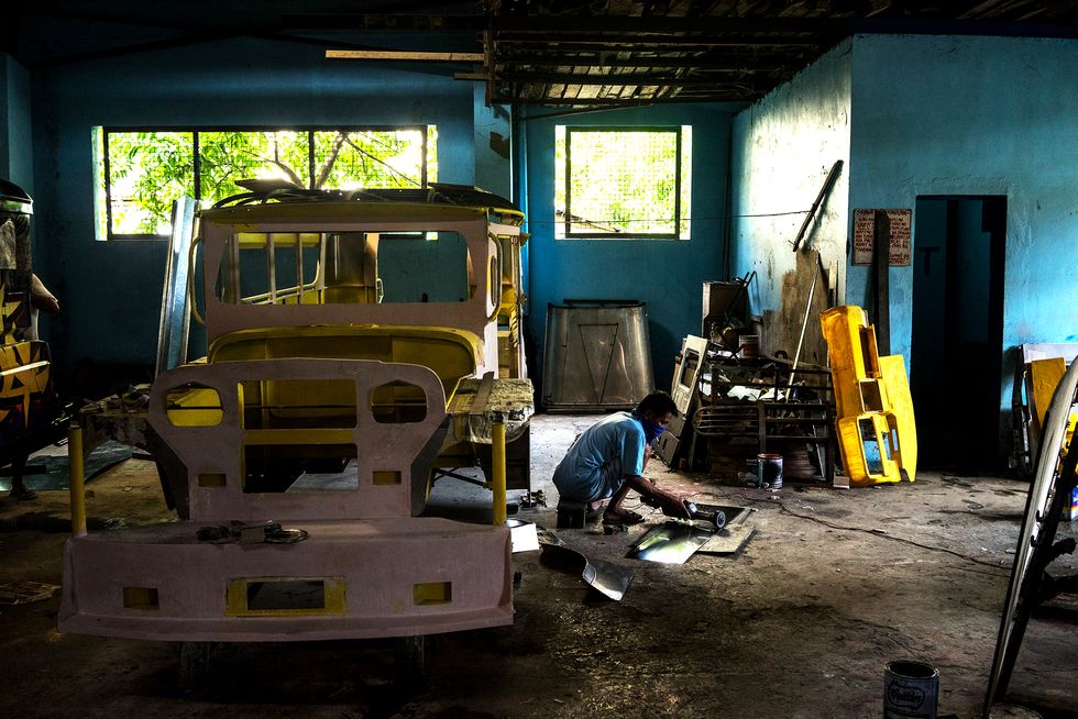 A mechanic works on the bodywork of a jeepney at the Morales Motors workshop in San Mateo, Rizal Province, the Philippines, on Monday, July 27, 2015. Philippine President Benigno Aquino boasted of record revenue and investment flows and a resurgent manufacturing sector during his administration, as he prepares to endorse a candidate for next year's election. 