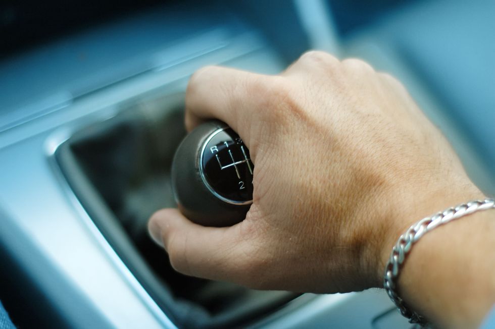Close up of a hand down-shifting a manual transmission car.