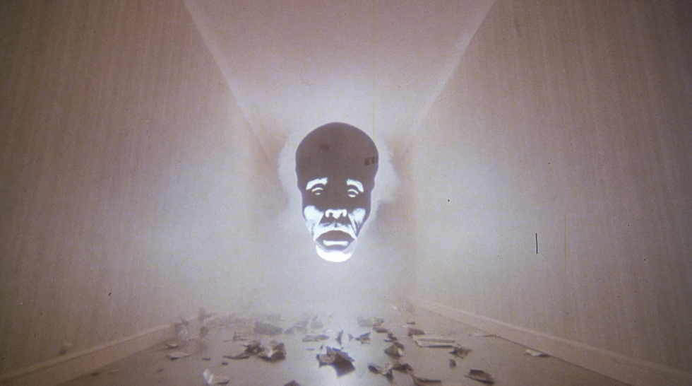 a giant floating head appears in smoke in a hallway