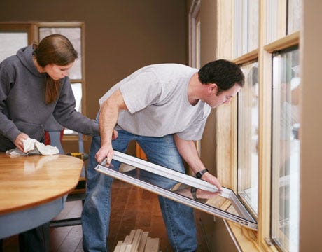 a man and woman install storm windows